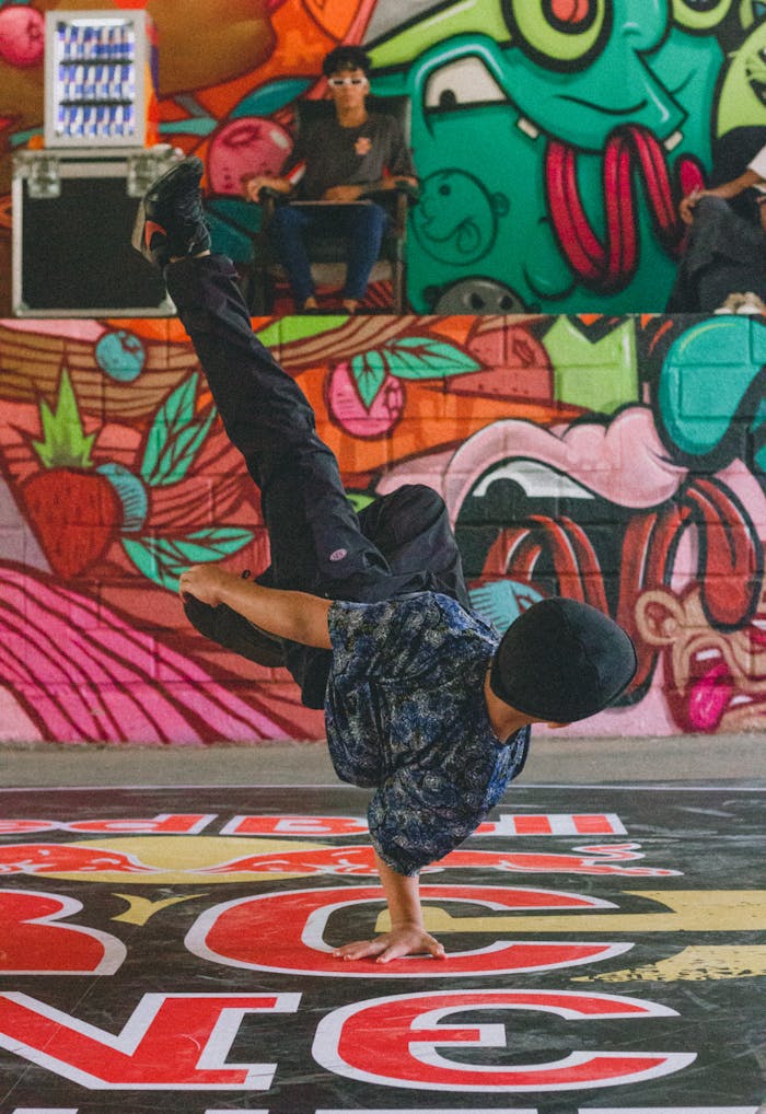 Vibrant street breakdancer showing impressive handstand against graffiti wall.